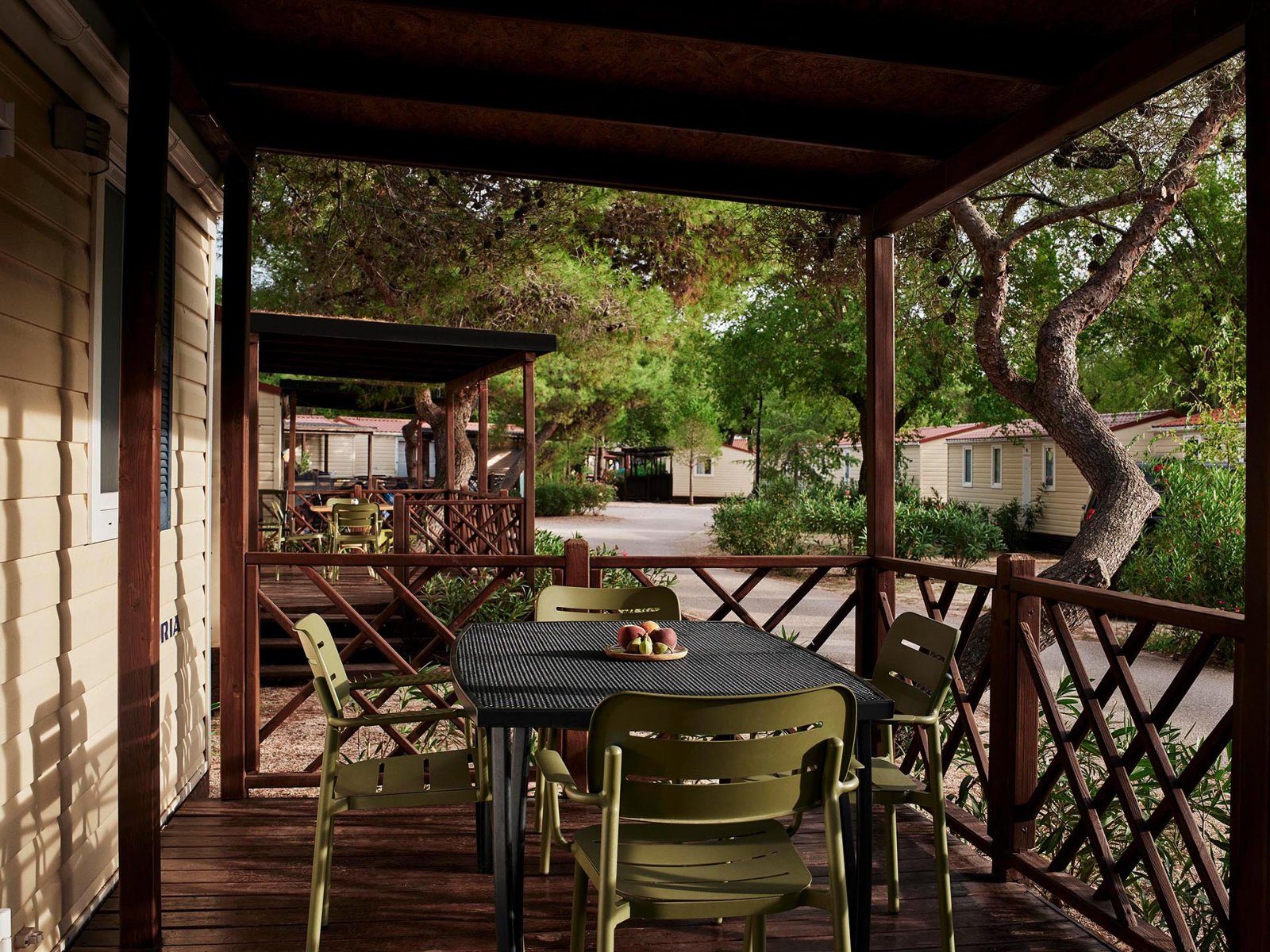 Shaded terrace of a Standard Mobile Home with a table and chairs under the pines