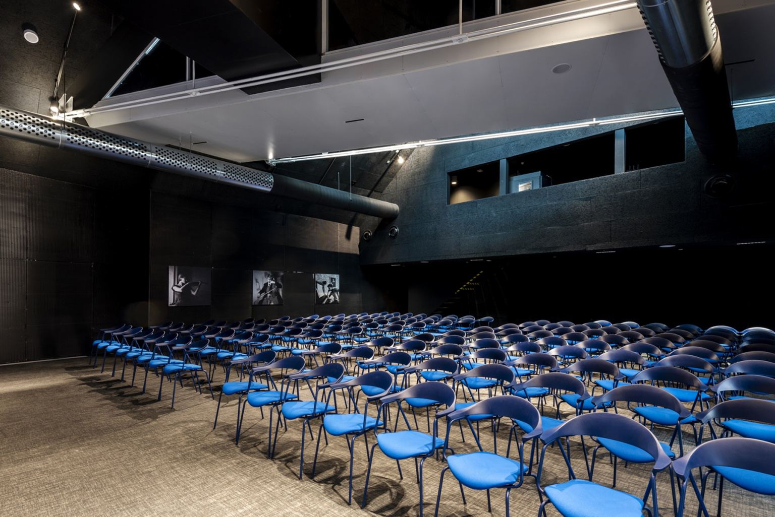 The concert hall at II Palaces in Zadar, its dark acoustic panelling and technical gallery above rows of blue seats set out for an audience