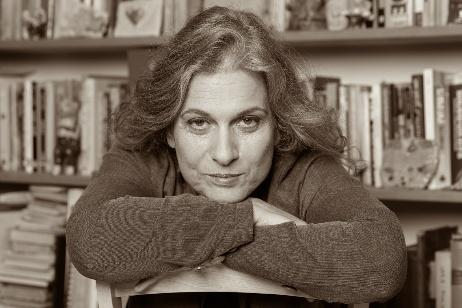 Tsipi Raz, documentary filmmaker, resting her chin on her arms before a wall of books